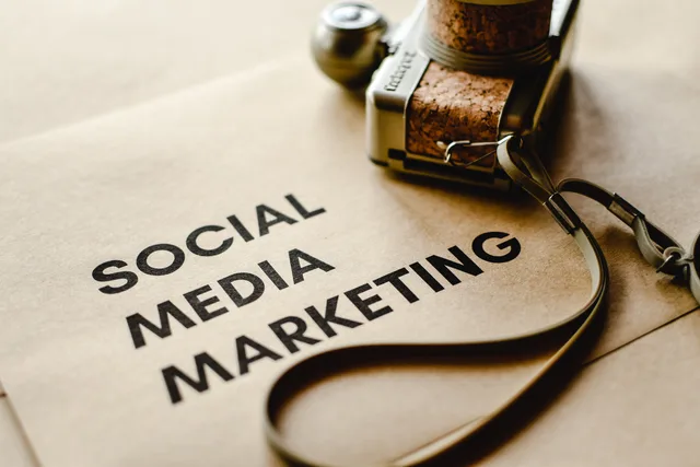 Close-up of a camera placed on brown paper with 'Social Media Marketing' text, emphasizing digital marketing themes. Paid social creative agency: why UK brands outsource ad design